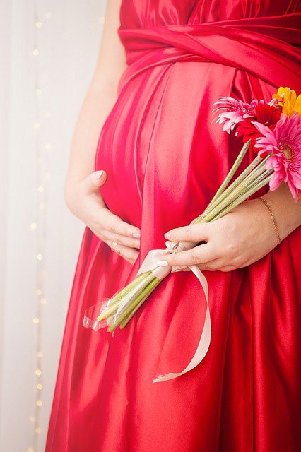 pregnant women holding her belly dressed in a gown in soul mothers pink colour