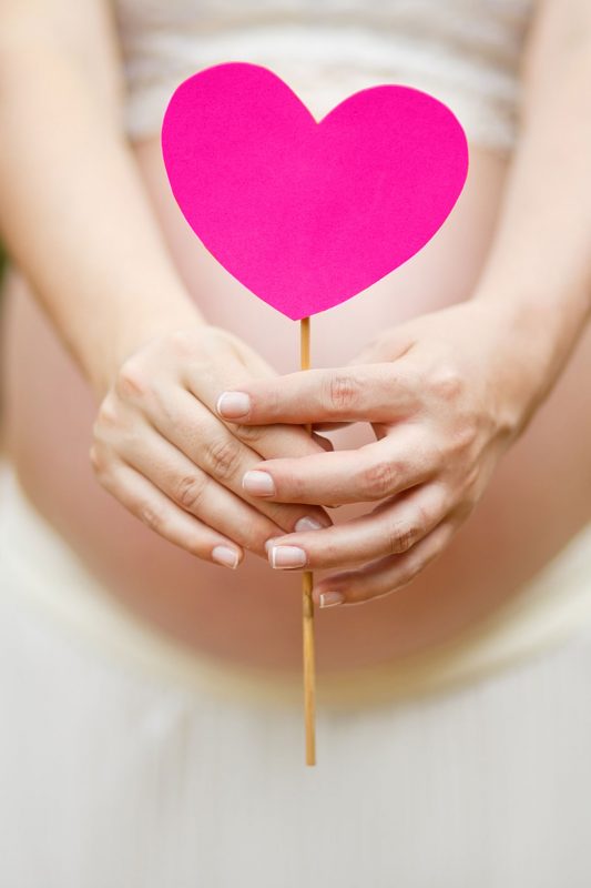 pregnant woman holding a pink heart in the soul mothers pink colour