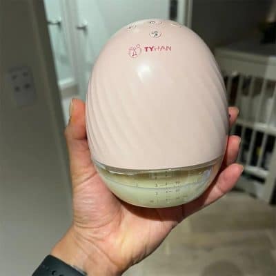 tyhan portable electric breast pump being held in a person's hand to show how compact it is.